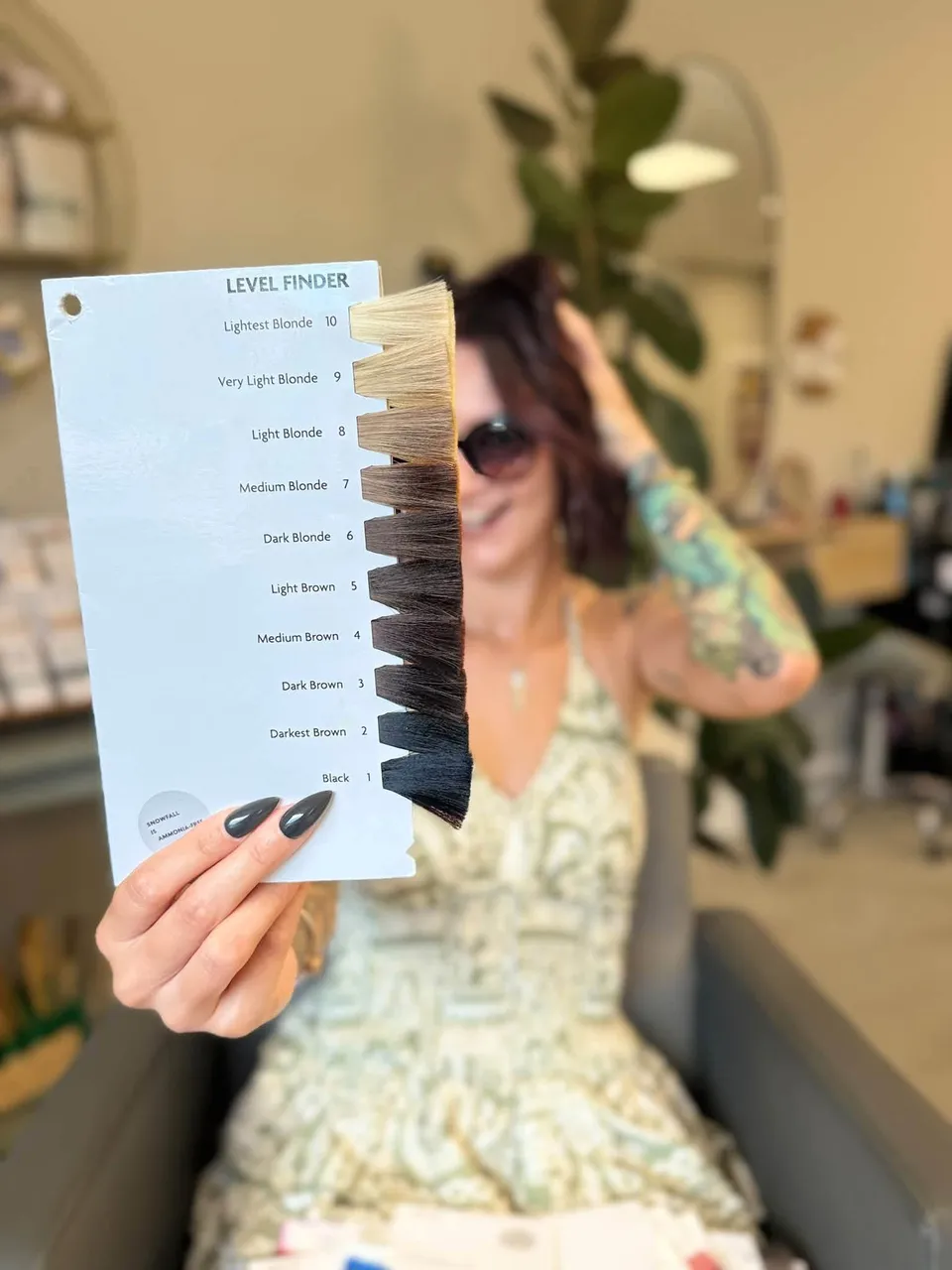 Em holding a hair level finder chart up to the camera, shades from lightest blonde to black.